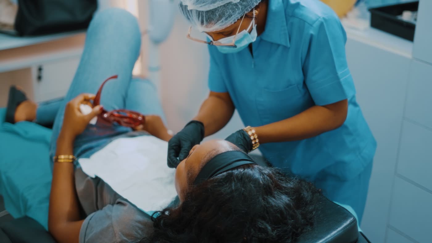 A dentist in teal scrubs examining a patient