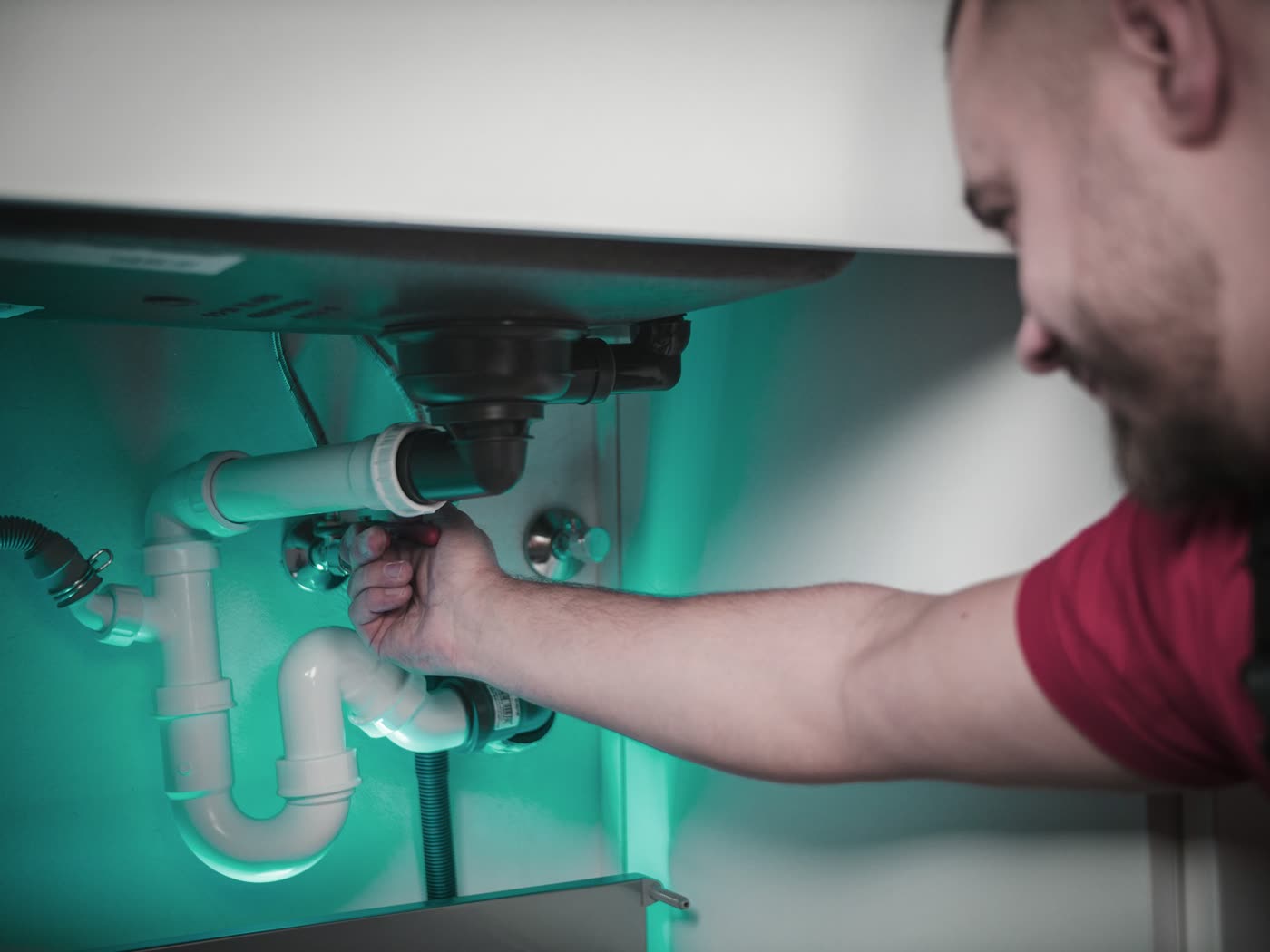 A plumber repairing the pipes under a kitchen sink
